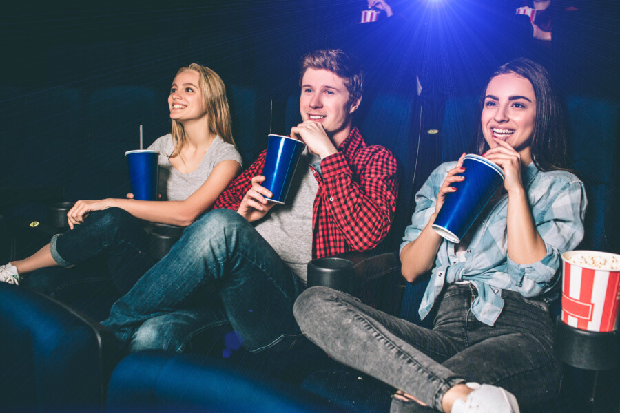 Kinobesucherinnen und Kinobesucher schauen einen Film und trinken Softgetränke