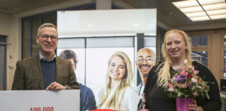 Hans-Martin Rump, Leiter der Agentur für Arbeit Kiel, überreicht der Kundin einen Blumenstrauß und eine Flasche alkoholfreien Rosmarin-Prosecco.