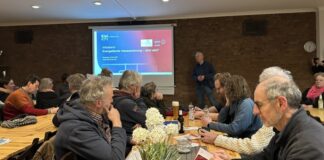 Welche Sanierung ist am effektivsten? Zuhörerinnen und Zuhörer im Vereinslokal des SV Hammer hören Energieberater Jasper Harten zu, der Mustersanierungskonzepte vorstellt