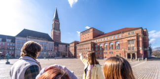Foto einer Gruppe von Menschen, die einen Stadtspaziergang durch Kiel macht und auf dem Rathausmarkt stehen