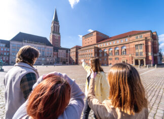 Foto einer Gruppe von Menschen, die einen Stadtspaziergang durch Kiel macht und auf dem Rathausmarkt stehen