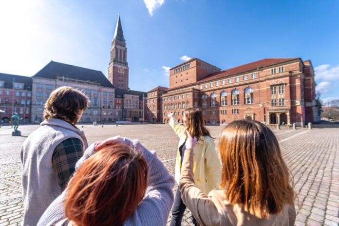 Foto einer Gruppe von Menschen, die einen Stadtspaziergang durch Kiel macht und auf dem Rathausmarkt stehen