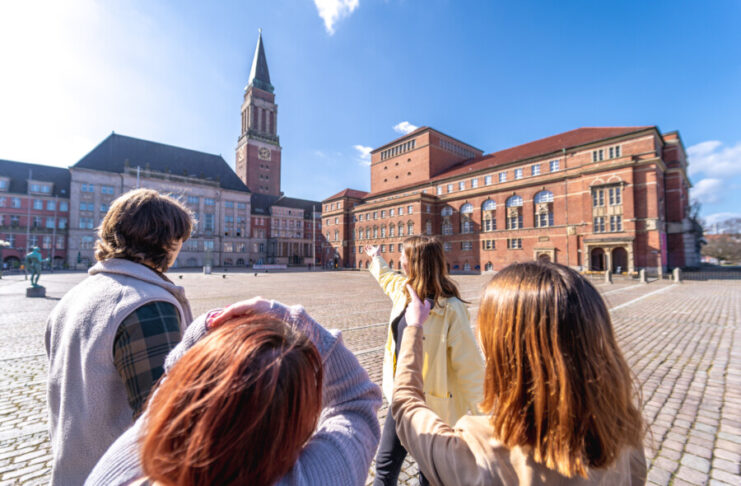 Foto einer Gruppe von Menschen, die einen Stadtspaziergang durch Kiel macht und auf dem Rathausmarkt stehen