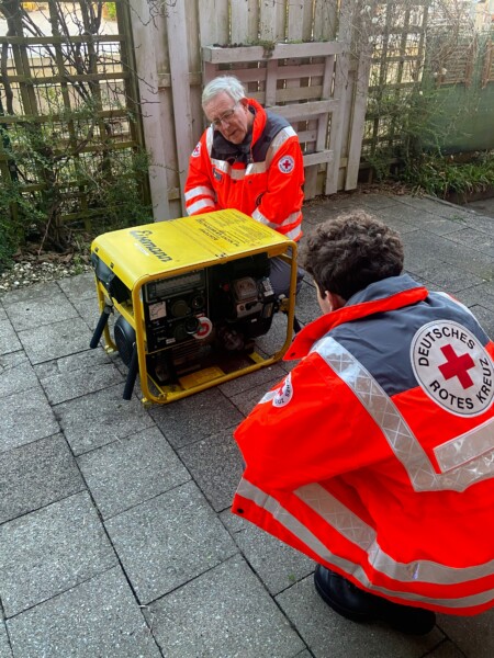 zwei Personen sitzen beim Stromaggregat