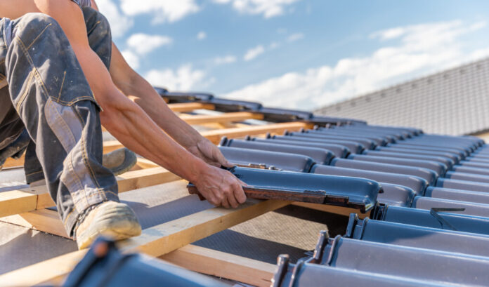 manufacture of the roof of a family house from ceramic tiles. copy space manufacture of the roof of a family house from ceramic tiles.