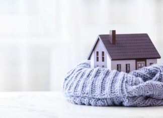 Kerndämmung in Kiel: Quartiersforum informiert Figure of house and warm scarf on table. Concept of heating season