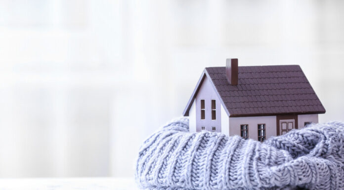 Figure of house and warm scarf on table. Concept of heating season